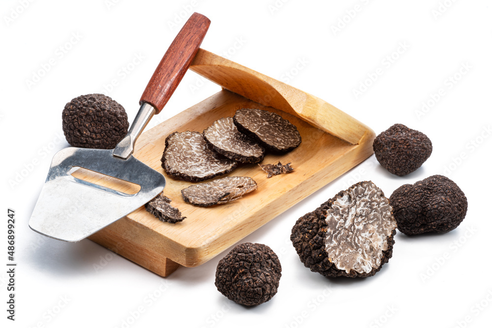 Fototapeta premium Slicing of black winter truffles isolated on white background.