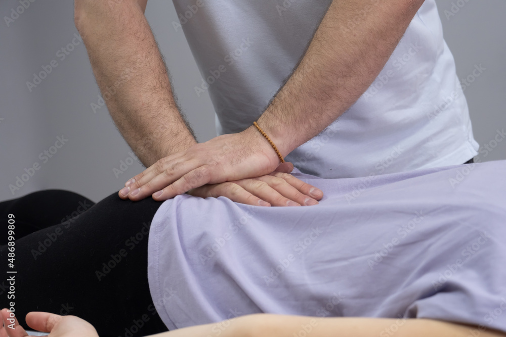 The osteopath works with the coccyx. The work process of a manual therapist. The patient lies on the couch. The doctor makes a correction of the coccyx zone