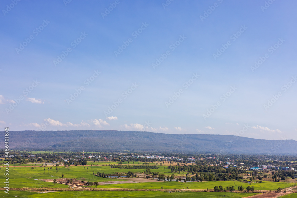 A panoramic view of the hills with villages, trees and rice fields with clouds in the sky.