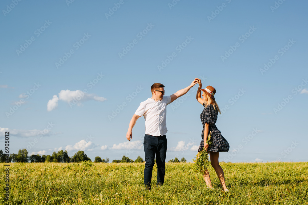 Happy laughing love couple dancing together in field on horizon on sunny day outdoors. Young caucasian heterosexual family romantic trip or walk in nature. Relationship, love concept Happy laughing love couple dancing together in field on horizon on sunny day outdoors. Young caucasian heterosexual family romantic trip or walk in nature. Relationship, love concept