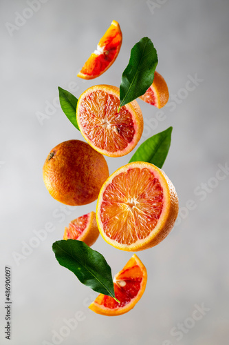 Bloody orange levitation. Oranges slices in the aer with green leaves. Abstract citrus fruit composition.