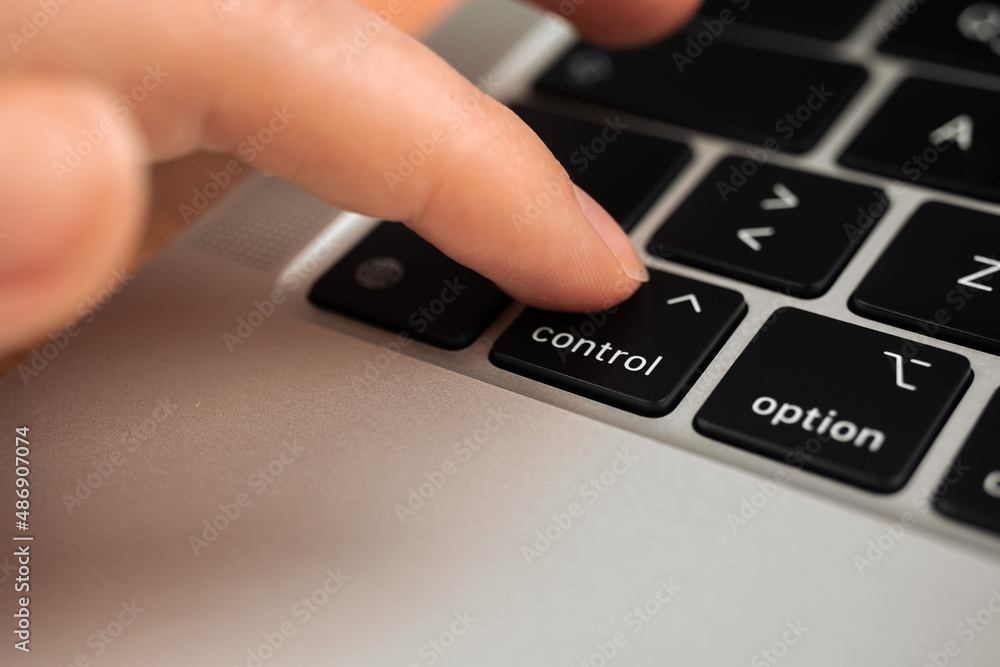 Hand pressing control key on modern laptop keyboard. Control sign and symbol close-up Hand pressing control key on modern laptop keyboard. Control sign and symbol close-up