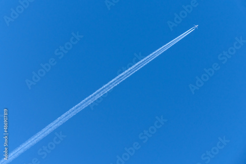 An airplane forming contrails in a blue sky