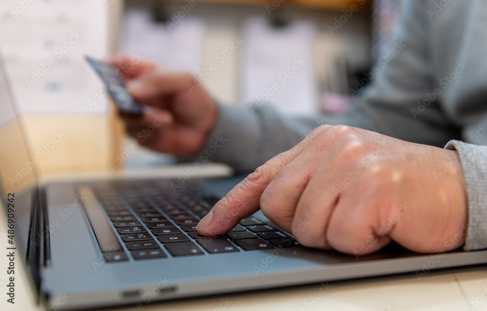 A person using a payment card to pay online. A person using a payment card to pay online.