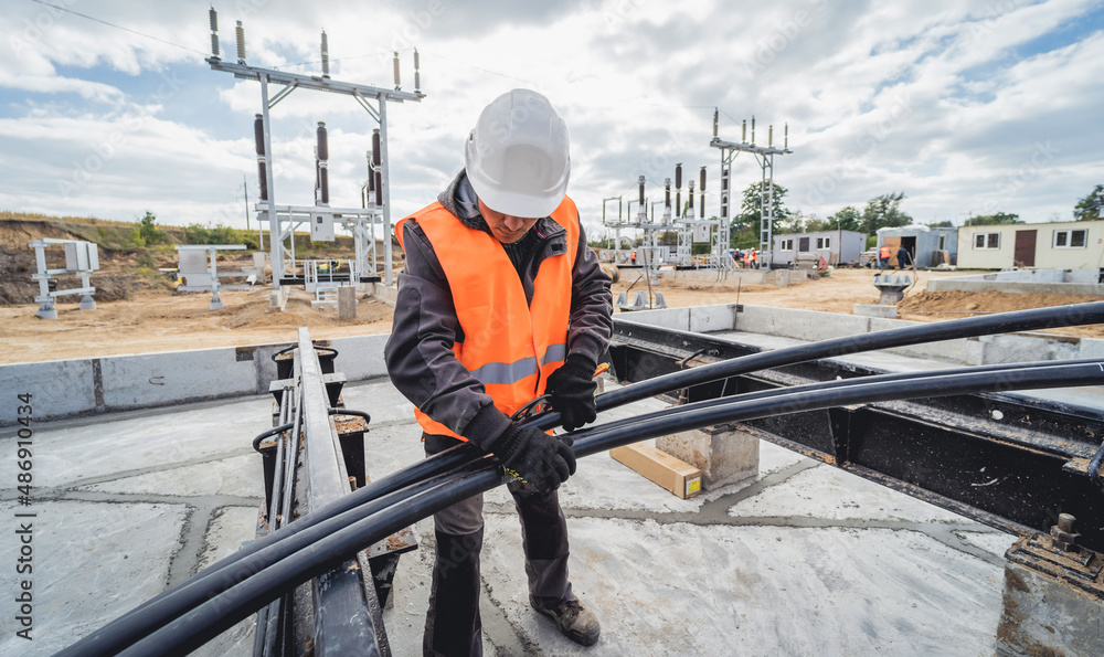 Foto Two electrician builder workers installing high-voltage cable