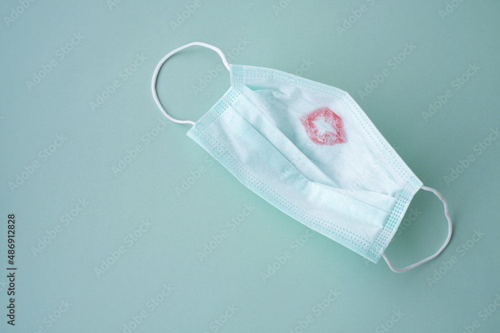 Protective medical face mask with red lipstick kiss print on a green background Protective medical face mask with red lipstick kiss print on a green background