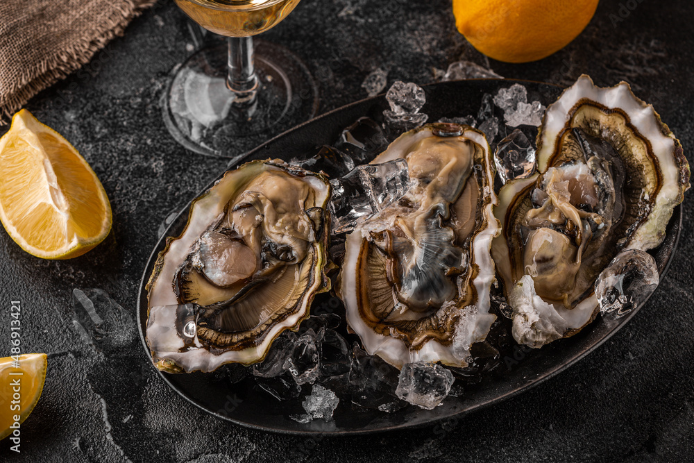 Fresh oysters close-up on ice served with lemon and wine. Fresh oysters close-up on ice served with lemon and wine.