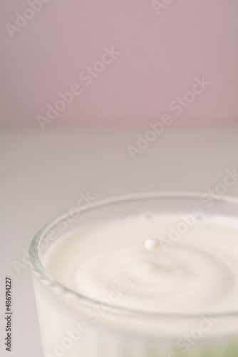 Milk drips into a transparent faceted glass.