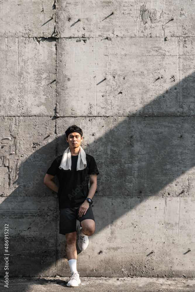 sports male resting against the wall with towel on his shoulder sports male resting against the wall with towel on his shoulder
