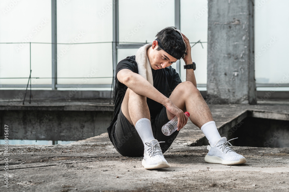 sportsman sitting on the ground is wiping sweat with towel sportsman sitting on the ground is wiping sweat with towel