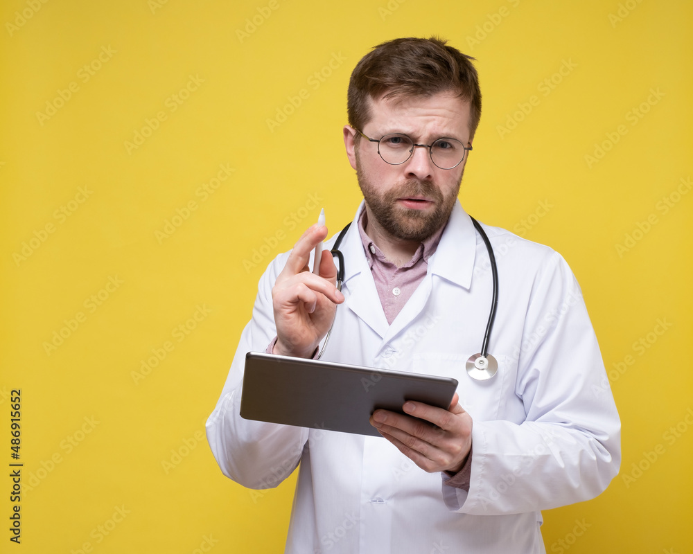 Focused doctor contemplating a diagnosis, holding a tablet and a stylus. Copy Space. Yellow background.