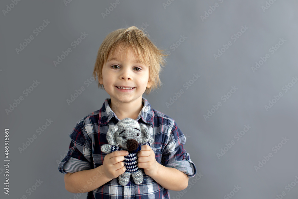Little toddler child, blond boy, playing with handmade little knitted toy Little toddler child, blond boy, playing with handmade little knitted toy
