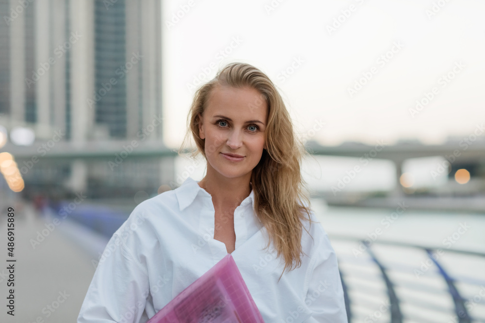 A beautiful business woman with a folder of documents in her hands outdoors. City portrait, business portrait