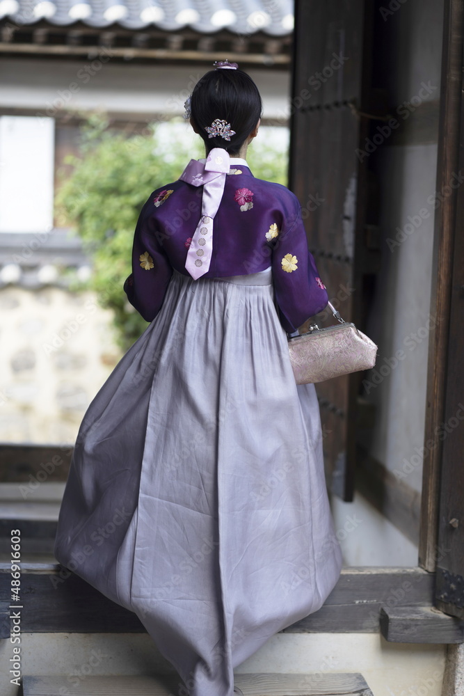 Woman in Hanbok standing at traditional Korean house Woman in Hanbok standing at traditional Korean house