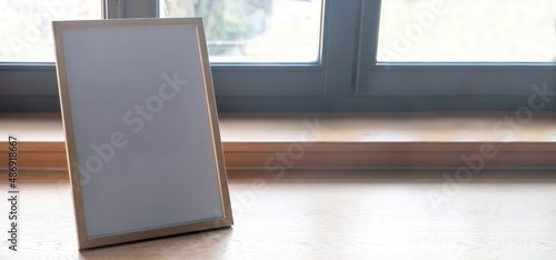 Valokuva Picture frame empty on a wooden table, home interior decoration, glass window ba