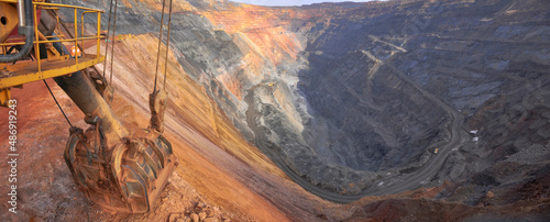 excavator bucket lies on the edge of the side of the iron ore quarry. Quarry panorama