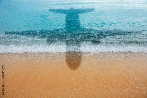 Schatten eines Flugzeugs an einem Strand an der Wasserlinie