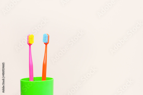 two multi-colored toothbrushes in a green glass. copy space..