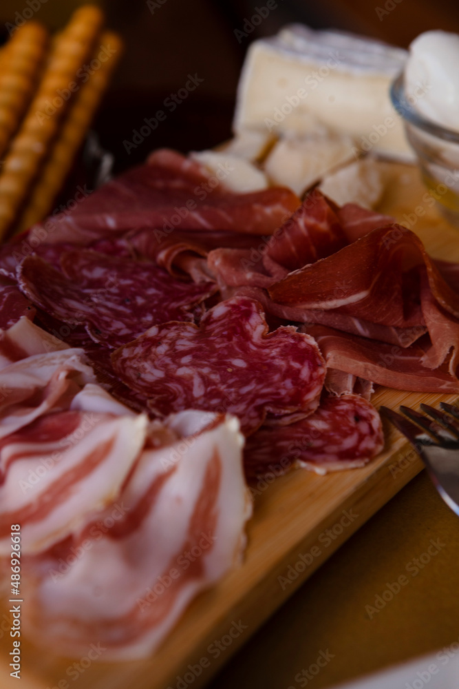 Cheese and meat board in an Italian restaurant in Cremona, Lombardy, Italy with mozzarella, prosciutto, salami, ham, brie, parmesan, bread sticks. Italian food in Europe. European antipasti and snacks