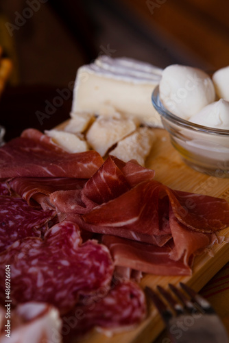 Cheese and meat board in an Italian restaurant in Cremona, Lombardy, Italy with mozzarella, prosciutto, salami, ham, brie, parmesan, bread sticks. Italian food in Europe. European antipasti and snacks
