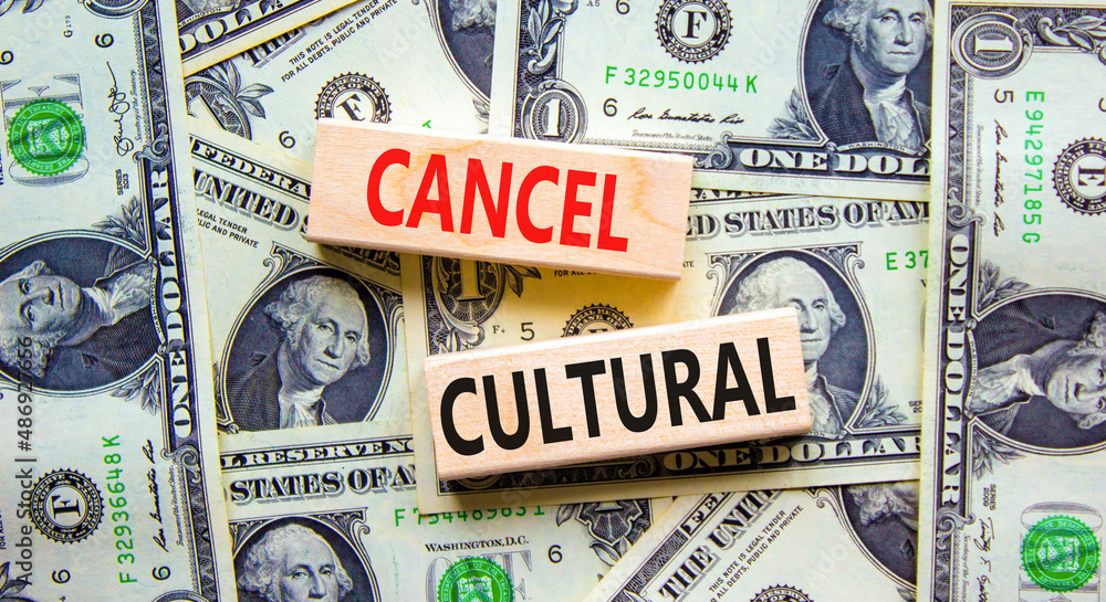 Cancel cultural symbol. Concept words Cancel cultural on wooden blocks on a beautiful background from dollar bills. Business and cancel cultural concept, copy space.