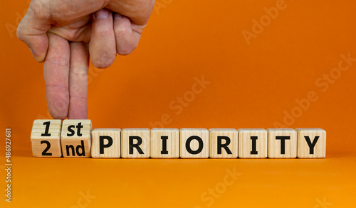 1st or 2nd priority symbol. Businessman turns wooden cubes and changes words 2nd priority to 1st priority. Beautiful orange background. Business, 1st first or 2nd second priority concept. Copy space. photo