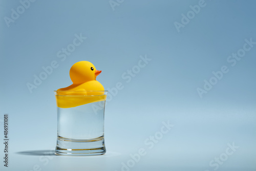 Fotografiet Yellow toy rubber duck floating in a glass of water.