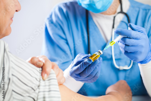 Female GP doctor holding ampoule vial with yellow liquid