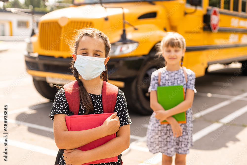 The schoolgirl puts on a mask to prevent colds and viruses. Medical concept. Back to school. Child going school after pandemic over.
