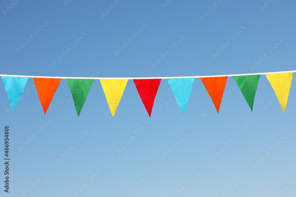 Bunting with colorful triangular flags against blue sky Bunting with colorful triangular flags against blue sky