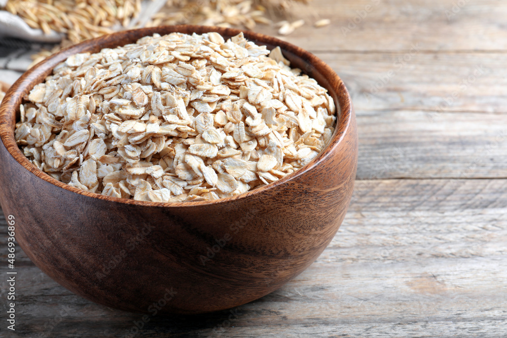Bowl with raw oatmeal on wooden table. Space for text Bowl with raw oatmeal on wooden table. Space for text