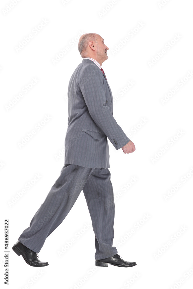 side view full length photo of a mid aged business man walking forward and looking away side view full length photo of a mid aged business man walking forward and looking away