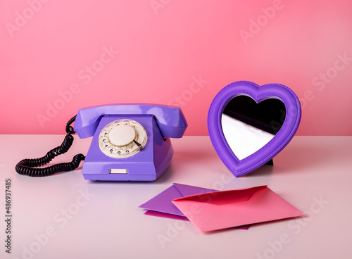 Retro phone on table with heart-formed mirror and envelopes. Valentine s day and love concept. High quality photo photo