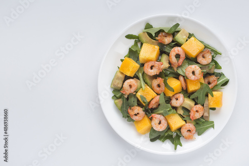Healthy delicious salad with mango fruits, avocado and fresh shrimp in a plate on a white background. Healthy food. Proper nutrition.