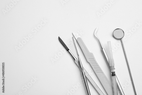 Set of different dentist's tools and syringe on light background, flat lay. Space for text