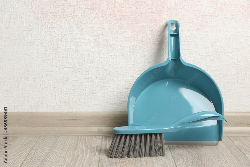 Plastic whisk broom with dustpan near light wall indoors. Space for text - obrazy, fototapety, plakaty 