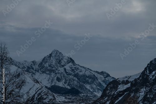Beautiful winter mountain landscape at the sunrise with dramatics clouds. High snow covered mountains in the fog. 