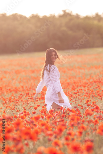 Beautiful girl in a white dress on a poppy field