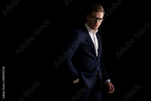 side view of sexy young man in suit with glasses holding hand in pocket