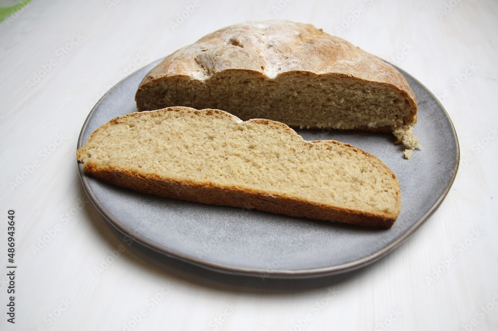 Fresh just baked rye bread loaf and slice on gray plate on white background Fresh just baked rye bread loaf and slice on gray plate on white background