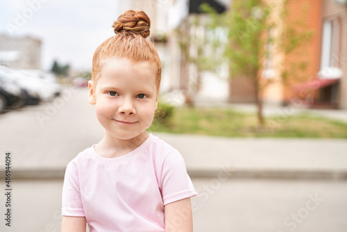 Little girl outdoor portrait. Red hair. Happy baby face. Female person at backyard. American smart schoolgirl. Positive child expression. Smile kid face. Summer time © elenavolf
