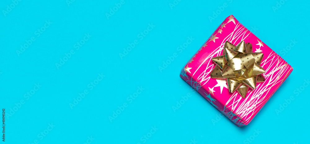 Pink square gift box with gold bow, blue banner with text space, top view Pink square gift box with gold bow, blue banner with text space, top view