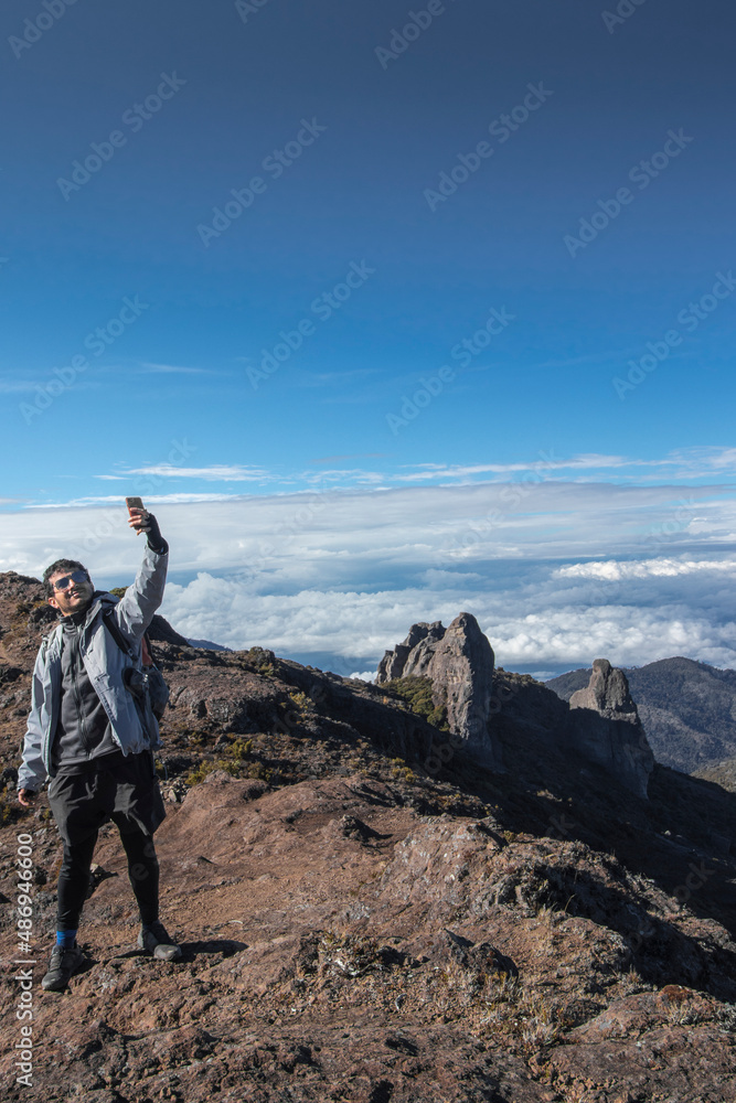 man taking a selfie with a background of rocky mountains with paramo vegetation in Chirripo National Park