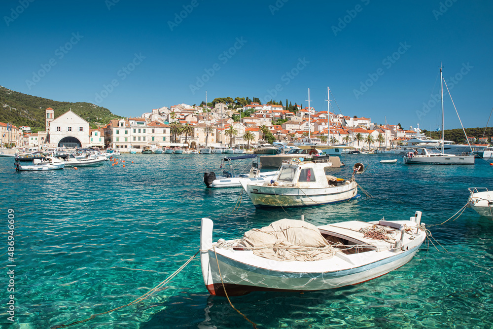 Harbor with boats in turquoise waters on island Hvar, Croatia with old town on background. Touristic resort
