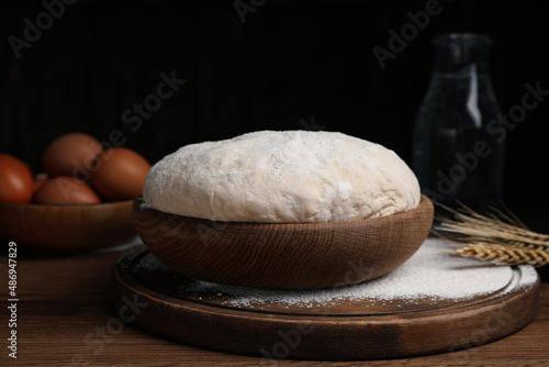 Dough in bowl on wooden table against black background. Sodawater bread recipe