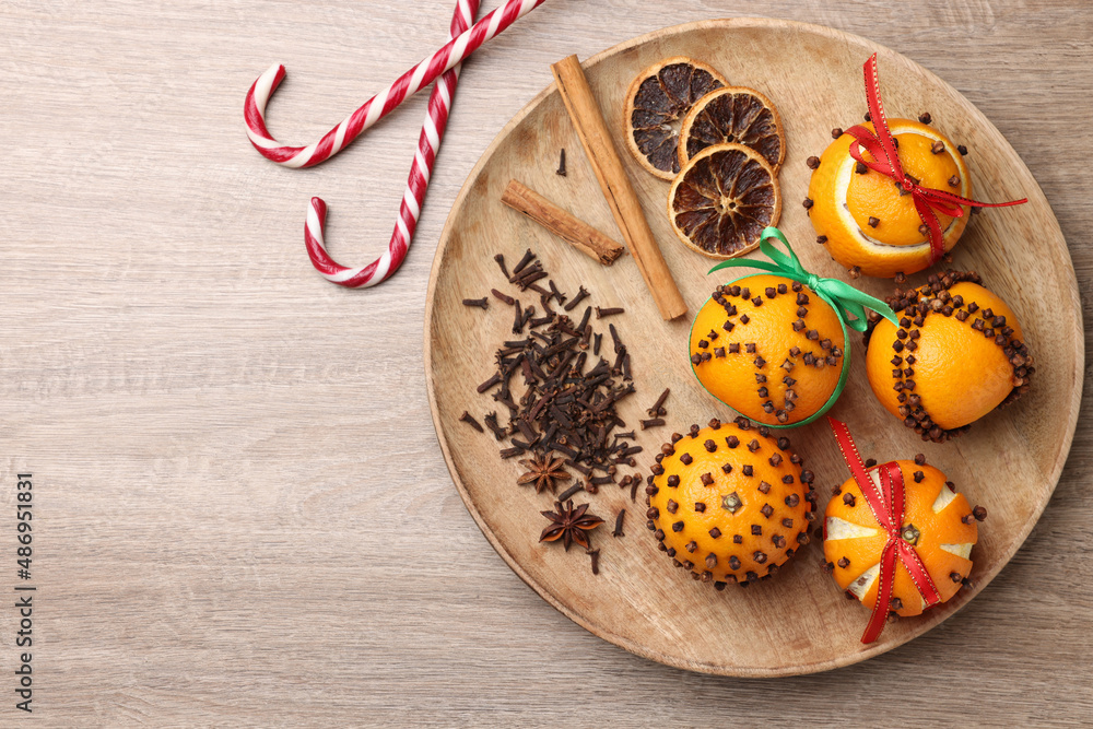 Pomander balls made of tangerines with cloves and candy canes on wooden table, flat lay. Space for text Pomander balls made of tangerines with cloves and candy canes on wooden table, flat lay. Space for text