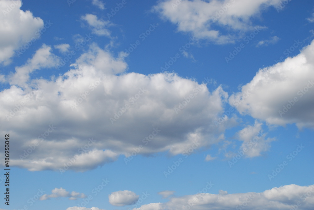 White clouds in a clear blue sky. Small cumulus clouds float across the light blue sky. They form a small group next to each other. Clouds of various shapes and sizes. White clouds in a clear blue sky. Small cumulus clouds float across the light blue sky. They form a small group next to each other. Clouds of various shapes and sizes.
