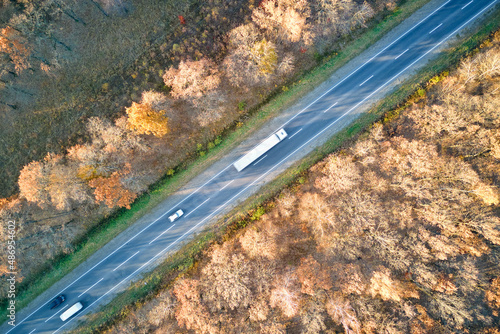 Aerial view of semi-truck with cargo trailer driving on highway hauling goods in evening. Delivery transportation and logistics concept