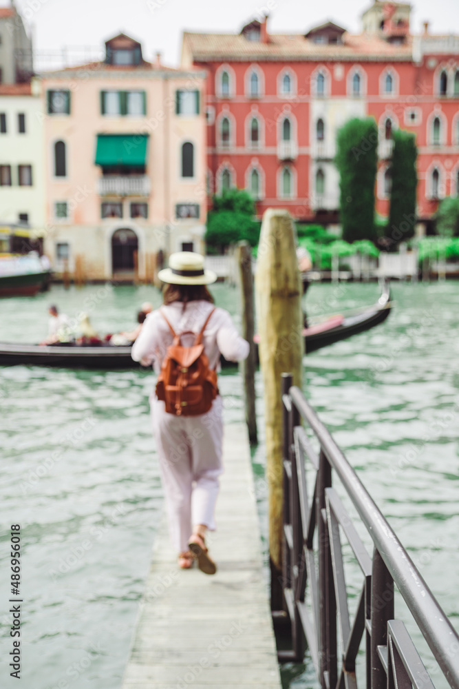 woman walking by wooden pier looking at grand canal at venice