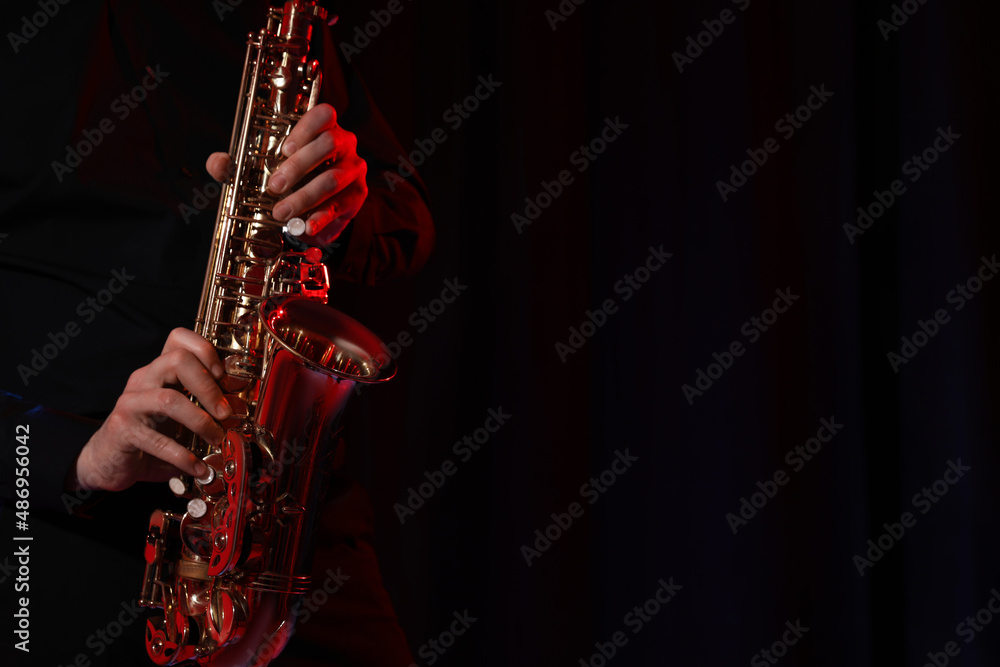 Fototapeta premium Man with saxophone on dark background, closeup. Space for text